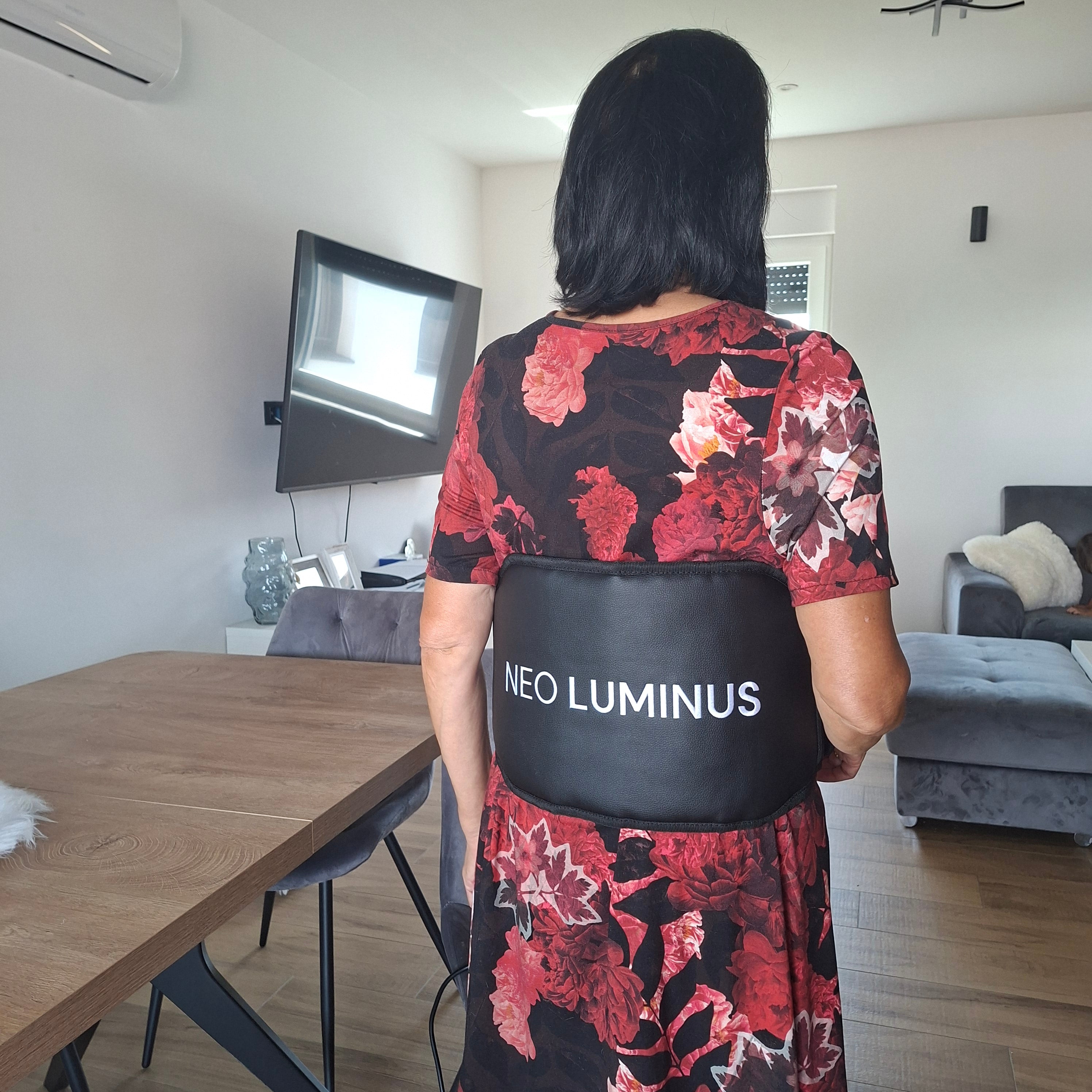Woman wearing a NEO LUMINUS light therapy pad in a home setting